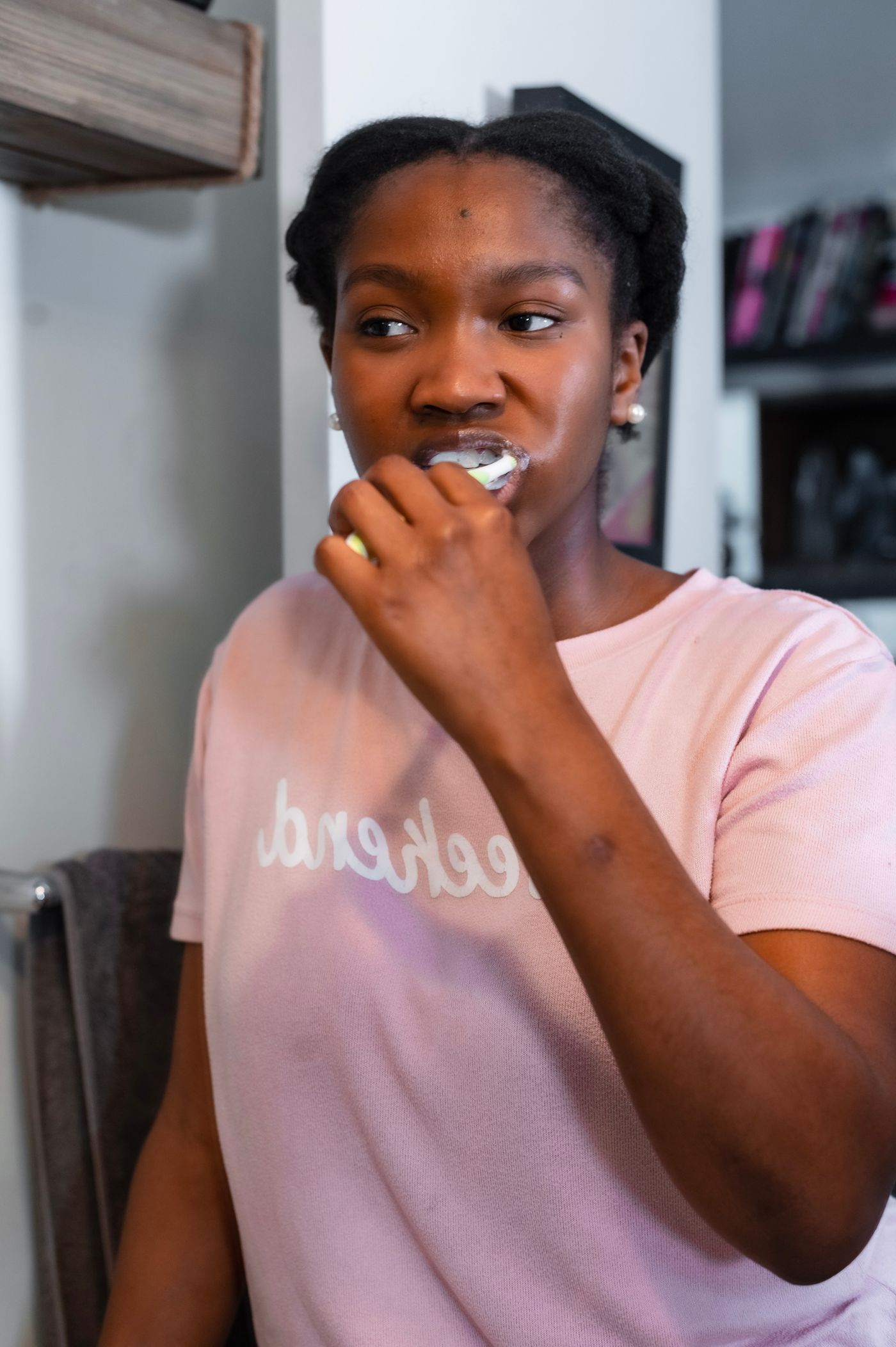 A woman brushing her teeth wearing a pink top