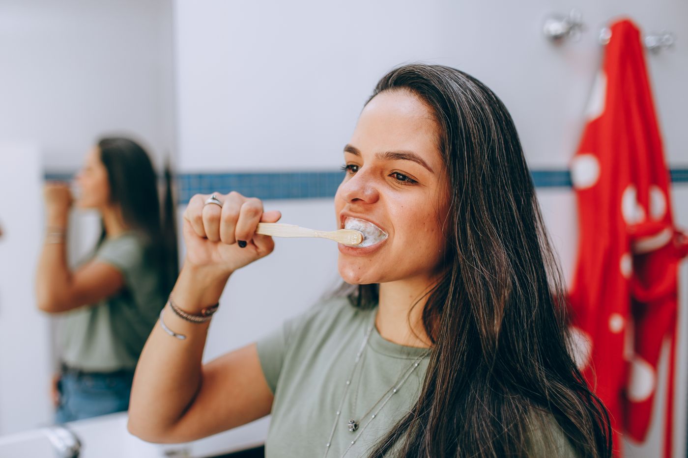 A young woman brushing her teeth in a bright bathroom
