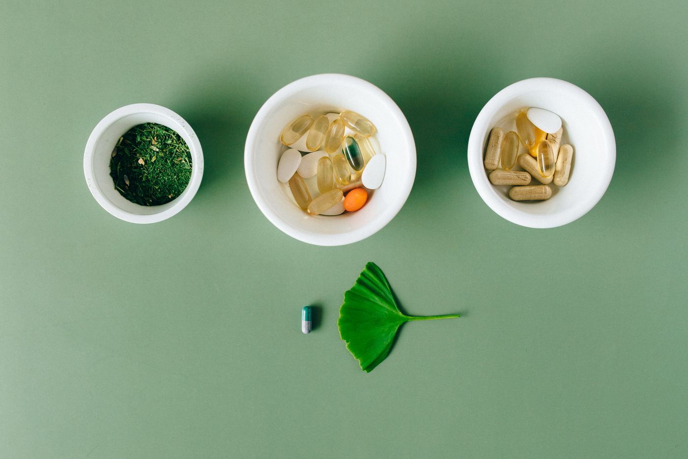 Capsules and dried herbs arranged in small ceramic bowls