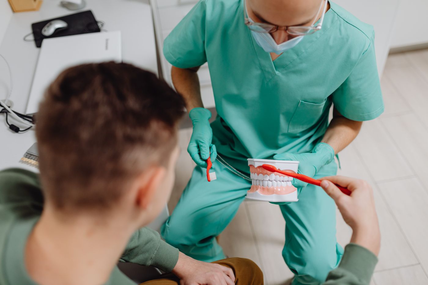 A dental professional showing a patient how to brush using a model