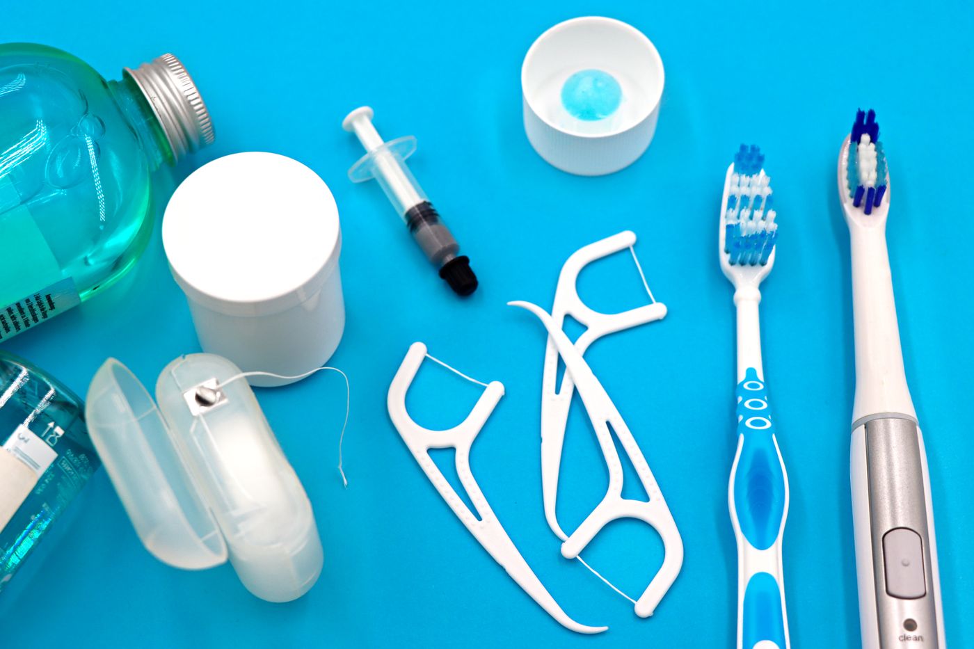 Toothbrushes, floss and rinse arranged on a blue background