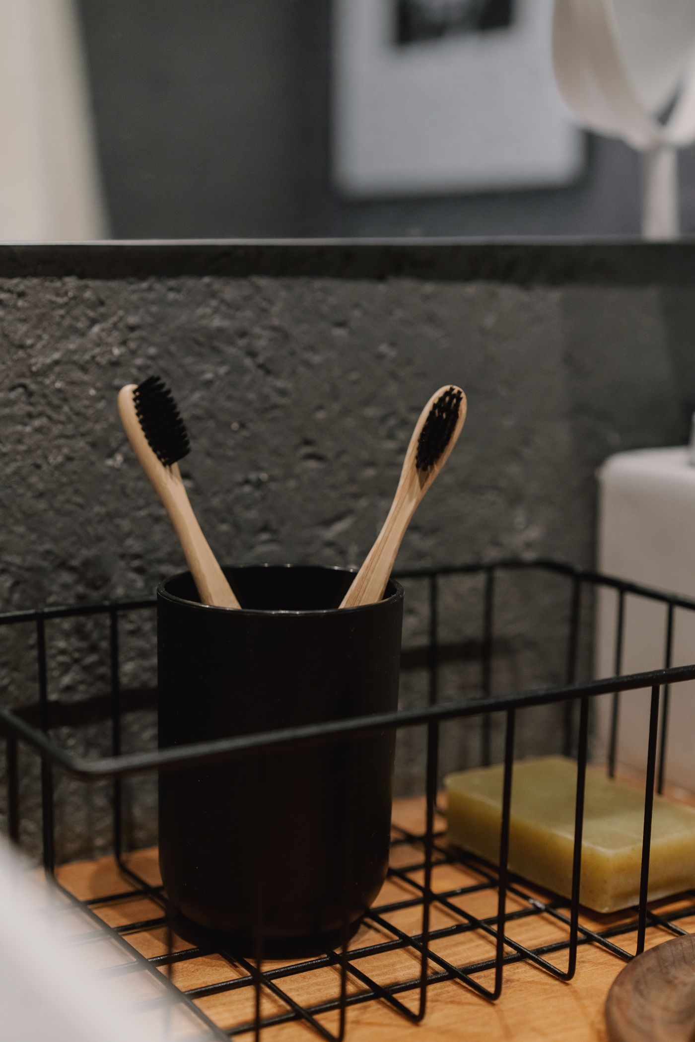 Two bamboo toothbrushes in a dark holder in a modern bathroom