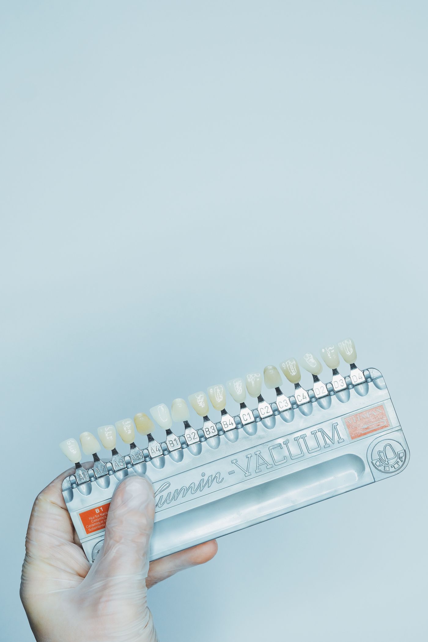A dental shade guide held up to compare tooth colour