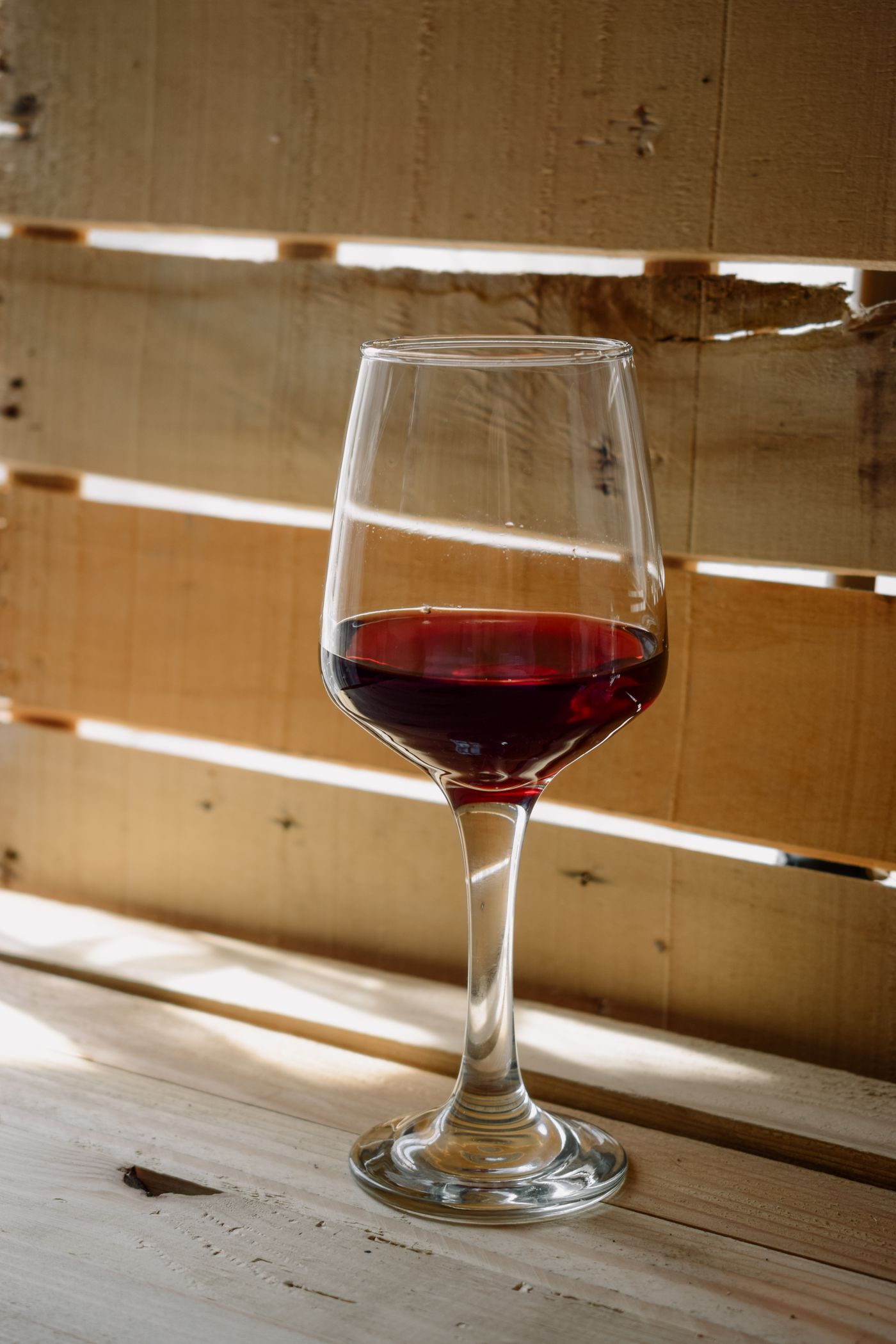 A glass of red wine on a rustic wooden surface